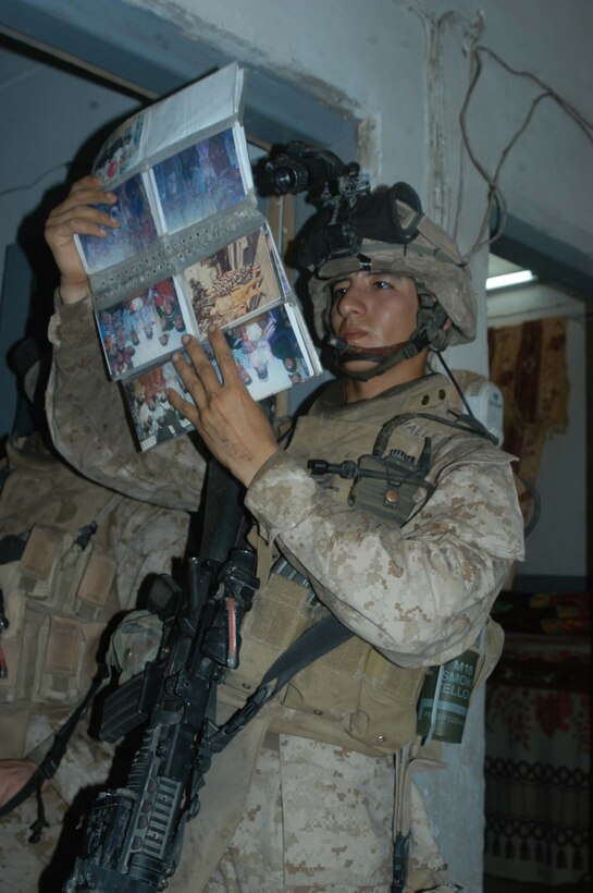 AR RAMADI Iraq (July 2, 2005)  --Lance Cpl. Manuel Valle Jr., a rifleman and team leader with 2nd Squad, 1st Platoon, Company A, 1st Battalion, 5th Marine Regiment, checks a photo album for propaganda he found in an Iraqi family's house during a mission in the city here early July 2. The 22-year-old from Parlier, Calif., and fellow Company A Marines conducted a raid in the Al Anbar capital between midnight and 5 a.m. and apprehended three insurgents. Photo by: Cpl. Tom Sloan