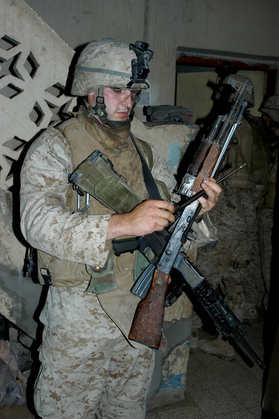 AR RAMADI Iraq (July 2, 2005)  --Lance Cpl. Mark T. McAuliffe, an assault man with 2nd Squad, 1st Platoon, Company A, 1st Battalion, 5th Marine Regiment, takes an AK-47 apart while other Marines search a house during a mission in the city here July 2. The 23-year-old from Seattle and fellow Company A Marines conducted a raid in the Al Anbar capital between midnight and 5 a.m. and apprehended three insurgents. Photo by: Cpl. Tom Sloan