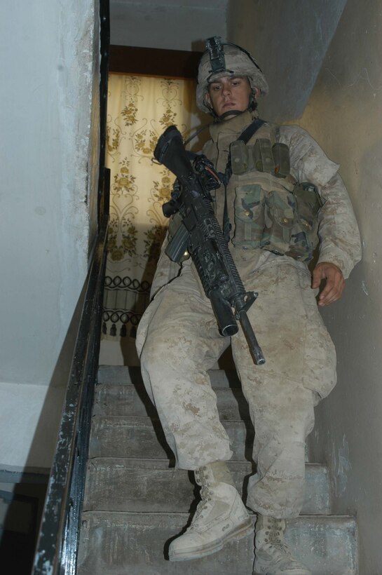 AR RAMADI Iraq (July 2, 2005)  -- Lance Cpl. Matthew V. Komatz, a grenadier and the point man for 2nd Squad, 1st Platoon, Company A, 1st Battalion, 5th Marine Regiment, walks down a flight of stairs after searching the upper deck of a house in the city here during a mission July 2. The 22-year-old Long Beach, Calif., native and fellow Company A Marines conducted a raid in the Al Anbar capital between midnight and 5 a.m. and apprehended three insurgents. Photo by: Cpl. Tom Sloan