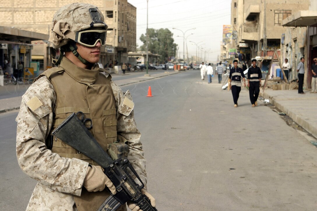 FALLUJAH, Iraq - Lance Cpl. Daniel Ramos, an infantryman with Surveillance, Target and Acquisition (STA) platoon, Company W, 1st Battalion, 6th Marine Regiment, provides security along a street corner here July 2.  The 19-year-old Orange Park, Fla. native worked alongside other Company W personnel, Iraqi Security Forces, and mechanized elements to conduct Operation Rolling Barrage, during which the troops blocked off sections of Fallujah while roving infantrymen patrolled through the streets to disrupt insurgent activity.