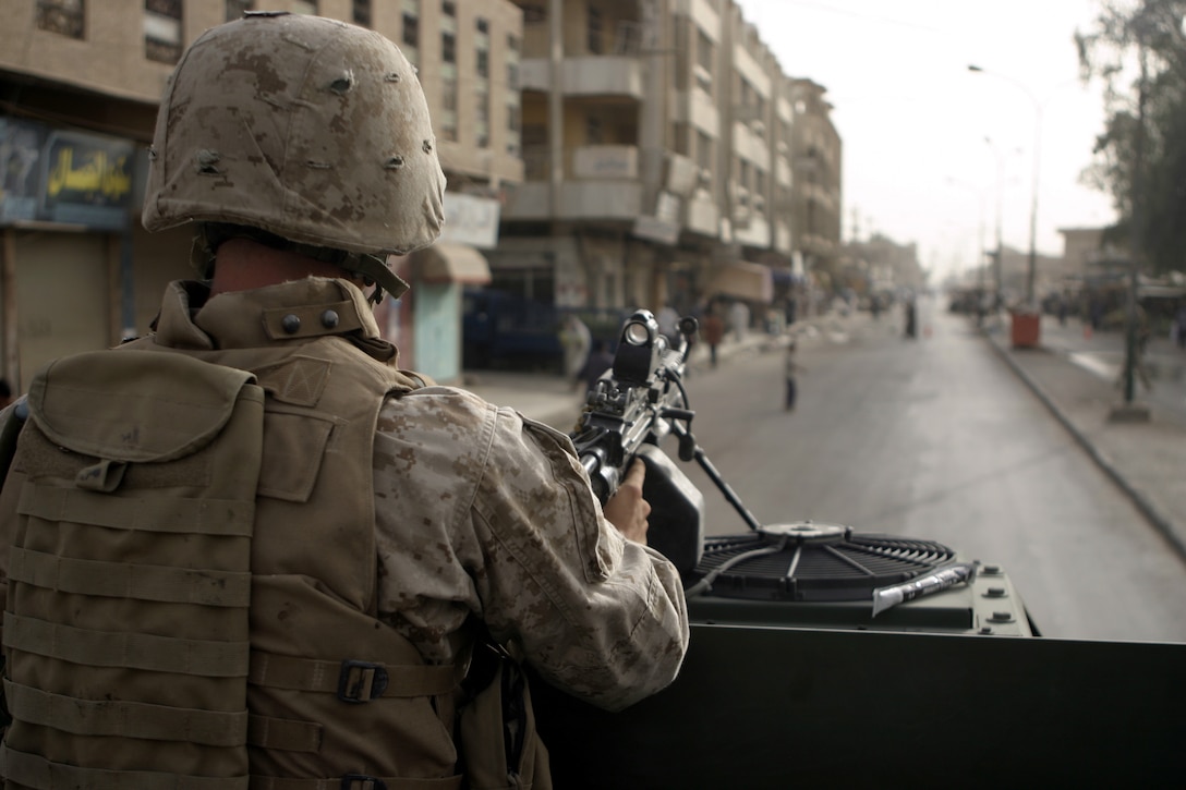 FALLUJAH, Iraq - A Marine with Company W, 1st Battalion, 6th Marine Regiment mans his M249 Squad Automatic Weapon atop his vehicle here July 2 while providing security down a street.  Company W worked alongside 1st Battalion, 6th Marine Regiment infantrymen, Iraqi Security Forces and mechanized supporting elements to conduct Operation Rolling Barrage, during which the troops blocked off sections of Fallujah while roving infantrymen patrolled through the streets to disrupt insurgent activity.