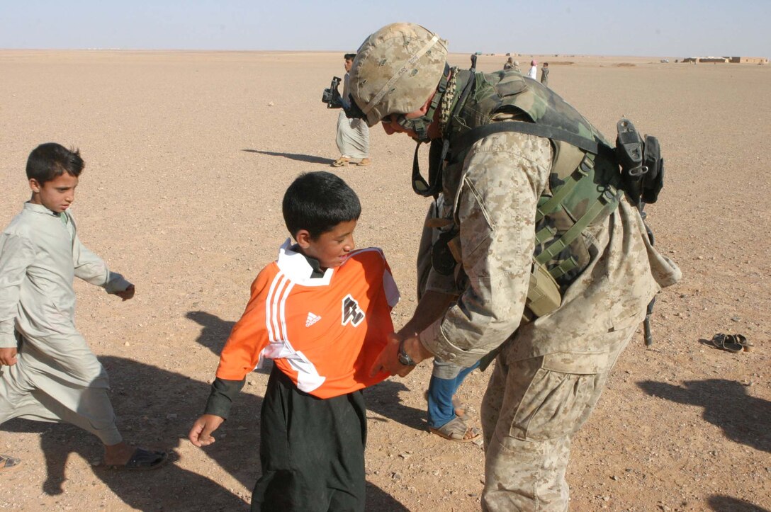 Cpl. Jeffrey H. Meighen, Civil Affairs Non-commissioned Officer, 5th Civil Affairs Group (CAG), 2d Light Armored Reconnaissance Battalion, Regimental Combat Team-2, gets the chance to make a difference in Iraqi children's lives during Operation Iraqi Freedom by handing out toys and hygiene products, participating in sporting events and helping to rebuild their towns.  Meighen helps a child from a local Iraqi village put on a soccer jersey for a game between the kids and Marines. (Photo by LCpl. Zachary W. Lester)