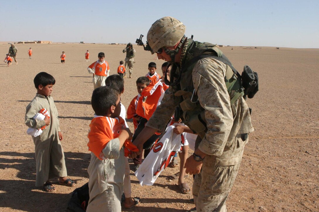 Cpl. Jeffrey H. Meighen, Civil Affairs Non-commissioned Officer, 5th Civil Affairs Group (CAG), 2d Light Armored Reconnaissance Battalion, Regimental Combat Team-2, gets the chance to make a difference in Iraqi children's lives during Operation Iraqi Freedom by handing out toys and hygiene products, participating in sporting events and helping to rebuild their towns.  Meighen helps a child from a local Iraqi village put on a soccer jersey for a game between the kids and Marines.(Photo by LCpl. Zachary W. Lester)