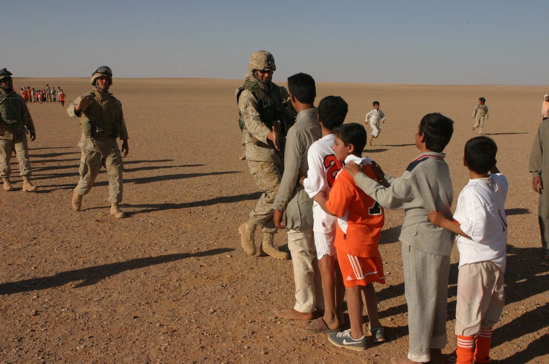 Cpl. Jeffrey H. Meighen, Civil Affairs Non-commissioned Officer, 5th Civil Affairs Group (CAG), 2d Light Armored Reconnaissance Battalion, Regimental Combat Team-2, gets the chance to make a difference in Iraqi children's lives during Operation Iraqi Freedom by handing out toys and hygiene products, participating in sporting events and helping to rebuild their towns.  Meighen high fives the Iraqi kids after a soccer game. (Photo by LCpl. Zachary W. Lester)