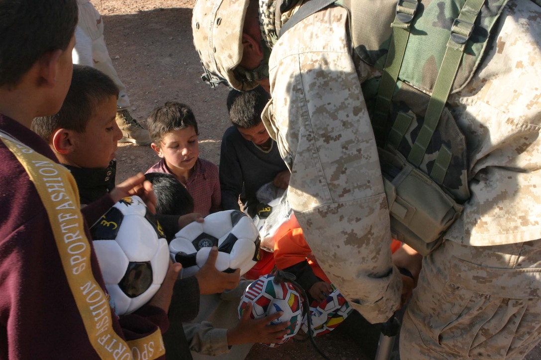 Cpl. Jeffrey H. Meighen, Civil Affairs Non-commissioned Officer, 5th Civil Affairs Group (CAG), 2d Light Armored Reconnaissance Battalion, Regimental Combat Team-2, gets the chance to make a difference in Iraqi children's lives during Operation Iraqi Freedom by handing out toys and hygiene products, participating in sporting events and helping to rebuild their towns. Meighen pumps air into soccer balls for the kids of a local village.  (Photo by LCpl. Zachary W. Lester)