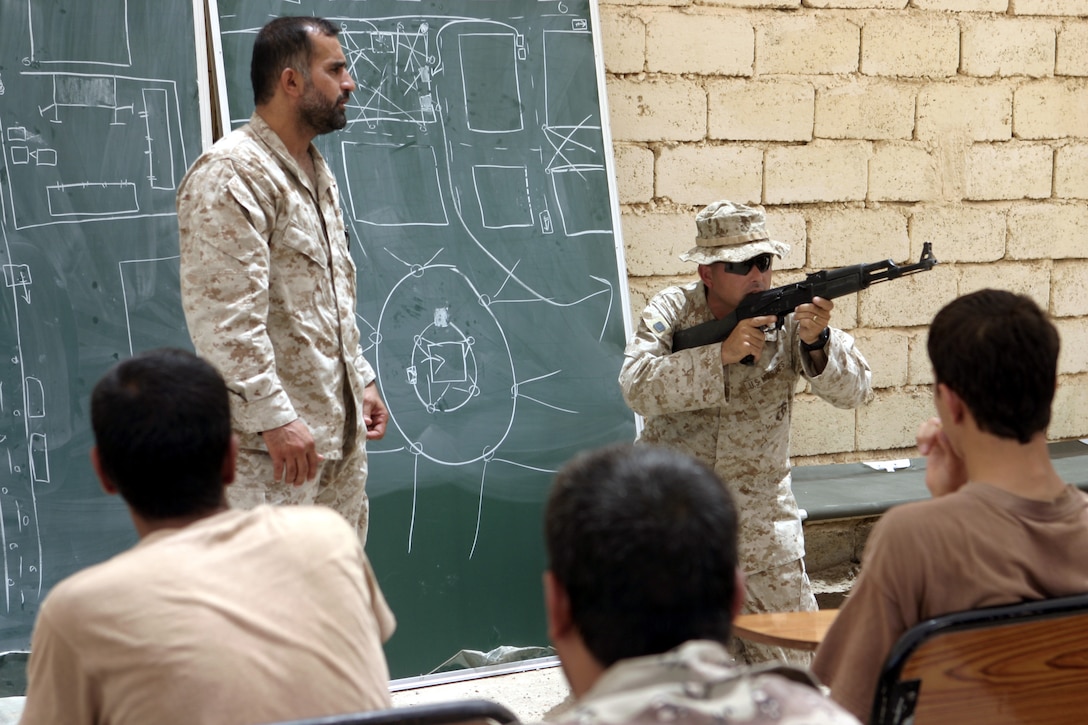 FALLUJAH, Iraq - Chief Warrant Officer-2 Kenneth Silvers, 1st Battalion, 6th Marine Regiment's gunner, shows a class of Iraqi soldiers and policemen proper weapons handling procedures during a class here Aug. 2.  Since mid-March, battalion personnel have trained approximately 600 Iraqi personnel on topics such as first aid in combat, infantry tactics, and convoy driving skills.  Iraqi forces are fully integrated into every operation the battalion's Marines and sailors conduct in and around the city.