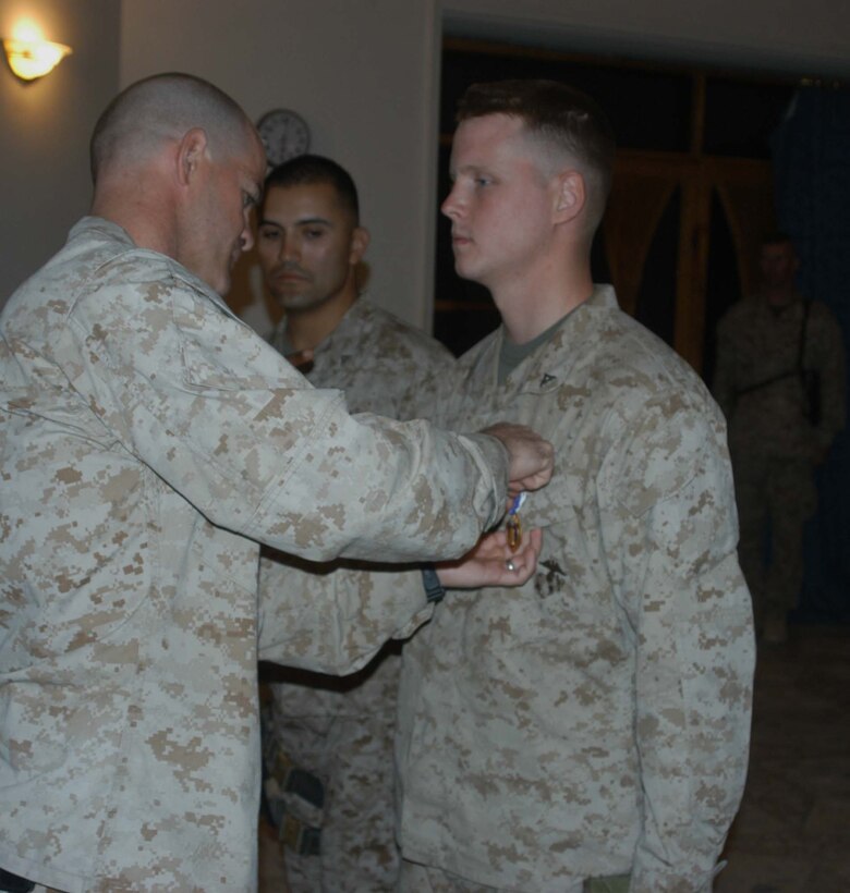 CAMP HURRICANE POINT Ar Ramadi, Iraq (Aug. 3, 2005) - Captain Michael J. Butler, commanding officer of Company W, 1st Battalion, 5th Marine Regiment, pins a Purple Heart on the chest of  Joseph P. Nagel, a machine gunner with Company W's 4th Platoon, during a ceremony here Aug. 2.. The 22-year-old from Dousman, Wis., was combat meritoriously promoted to the rank of corporal and received two Purple Hearts during the ceremony. Nagel was wounded June 15 and July 1 while conducting security and stability operations with his fellow Marines in support of Operation Iraqi Freedom. An enemy bullet hit Nagel in the left forearm and shrapnel from an improvised explosive caught him in the left hand. He was riding in the turret of a humvee manning a MK-19 Grenade Launcher during both close calls, which resulted in minor injuries.  Nagel is two-time veteran of the fighting in Iraq. He was with 1st Battalion, 5th Marines last year for OIF II, fought in Fallujah and made it out unscathed. Photo by: Cpl. Tom Sloan