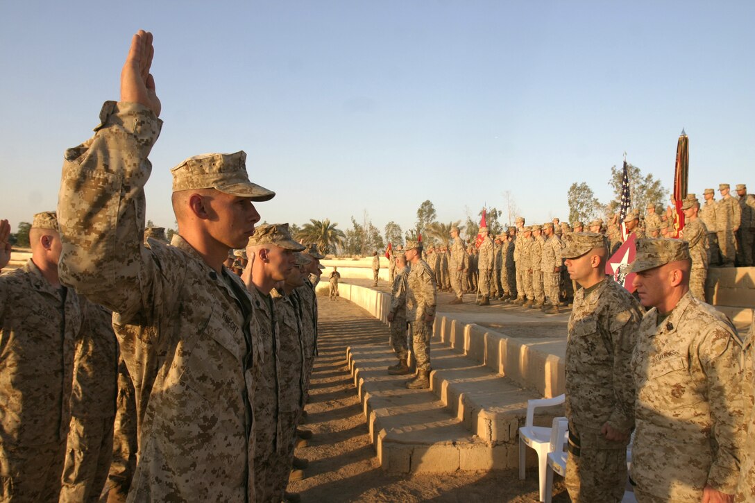 CAMP BAHARIA, Iraq - Forty-five Marines with 1st Battalion, 6th Marine Regiment raise their right hand to reaffirm their allegiance to the Corps during a mass reenlistment ceremony here Oct. 2.  Altogether, these personnel received approximately one million dollars in reenlistment bonuses, along with future duty station preference.