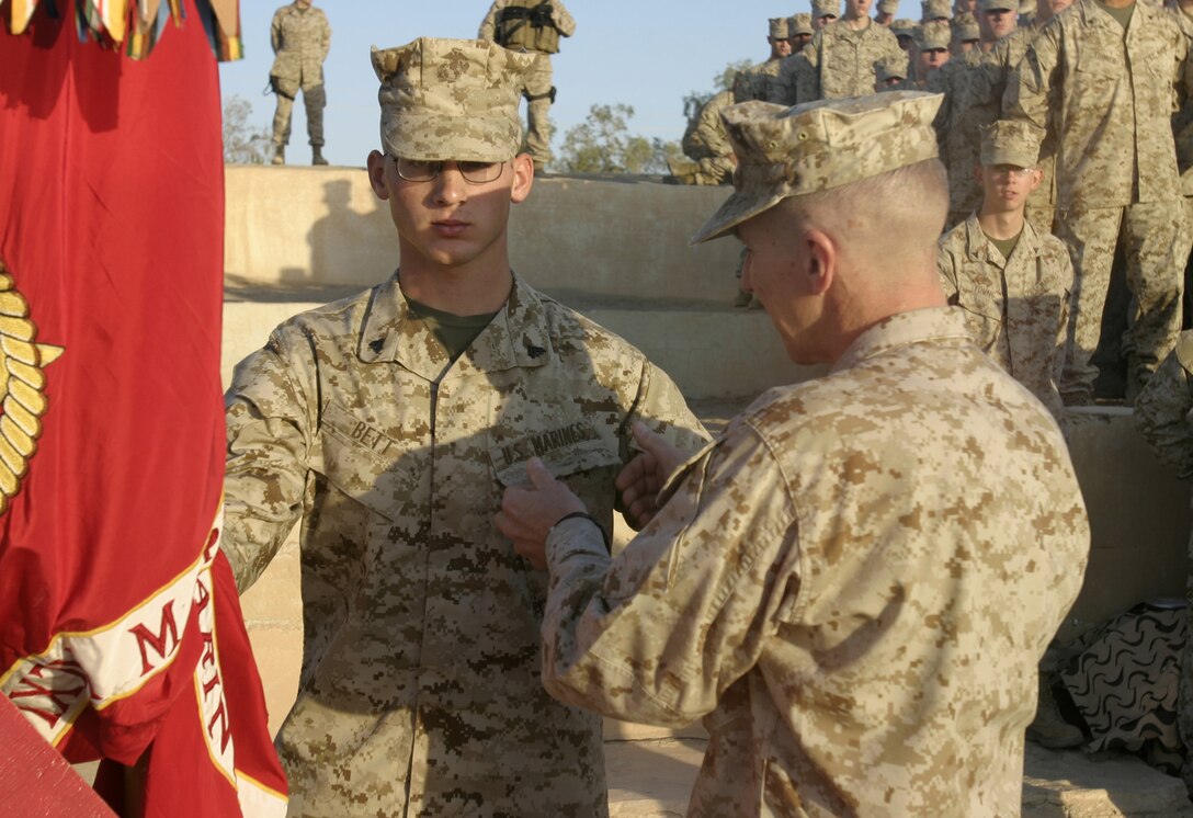 CAMP BAHARIA, Iraq - Corporal Ben Bett, a reenlisting infantryman with 1st Battalion, 6th Marine Regiment, receives a coin from Maj. Gen. Richard Huck, 2nd Marine Division's commanding general, during a reenlistment ceremony here Oct. 2.  Altogether, the 45 personnel reenlisting received approximately one million dollars in reenlistment bonuses, along with future duty station preferences.
