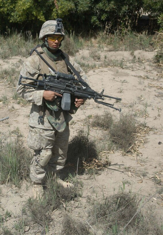 AR RAMADI, Iraq (April 2, 2005) - With weapon in hand, 23-year-old Lance Cpl. Greg R Allen, machine gunner, 1st Squad, 4th Platoon, Company B, 1st Battalion, 5th Marines, of Leicester, England, keeps a lookout for insurgents and other threats while conducting a weapons caches search with his fellow Company B devil dogs. Marines with 4th Platoon, Company B, 1st Battalion, 5th Marine Regiment and leathernecks of Company A, 1st Combat Engineer Battalion teamed up and discovered four 120 mm shells, a 155 mm shell; several live and empty 7.62 rounds, explosive detonation cord, a live fragmenting grenade and one rocket launcher during a five-hour search conducted on several acres of farmland along the banks of the Euphrates River on the edge of the city here. Photo by Cpl. Tom Sloan