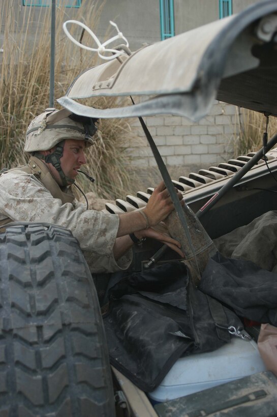AR RAMADI, Iraq (April 2, 2005) - Lance Cpl. Ryan K. Jones, machine gunner, 3rd Squad, 4th Platoon, Company B, 1st Battalion, 5th Marines, 21, of San Ramon, Calif., loads a heavy, 120 mm shell into the back of a Humvee. Marines with 4th Platoon, Company B, 1st Battalion, 5th Marine Regiment and leathernecks of Company A, 1st Combat Engineer Battalion teamed up and discovered four 120 mm shells, a 155 mm shell; several live and empty 7.62 rounds, explosive detonation cord, a live fragmenting grenade and one rocket launcher during a five-hour search conducted on several acres of farmland along the banks of the Euphrates River on the edge of the city here. Photo by Cpl. Tom Sloan