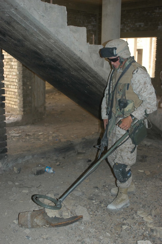 AR RAMADI, Iraq (April 2, 2005) - Lance Cpl. Michael B. Snyder, combat engineer, Company A, 1st Combat Engineer Battalion, 20, of Pickens, S.C., uses his metal detector to check the shape patterns of a 155 mm shell his fellow engineers found in an abandoned warehouse on the outskirts of the city here. Marines with 4th Platoon, Company B, 1st Battalion, 5th Marine Regiment and leathernecks of Company A, 1st Combat Engineer Battalion teamed up and discovered four 120 mm shells, a 155 mm shell; several live and empty 7.62 rounds, explosive detonation cord, a live fragmenting grenade and one rocket launcher during a five-hour search conducted on several acres of farmland along the banks of the Euphrates River on the edge of the city. Photo by Cpl. Tom Sloan