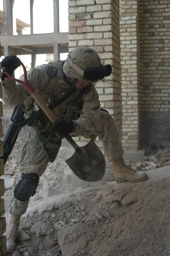 AR RAMADI, Iraq (April 2, 2005) - Twenty-year-old Lance Cpl. Nicholas H. Cole, combat engineer, Company A, 1st Combat Engineer Battalion, of Weaverville, Calif., uses his shovel to get to dig through a mount of dirt in an abandoned warehouse on the outskirts of the city here. Marines with 4th Platoon, Company B, 1st Battalion, 5th Marine Regiment and leathernecks of Company A, 1st Combat Engineer Battalion teamed up and discovered four 120 mm shells, a 155 mm shell; several live and empty 7.62 rounds, explosive detonation cord, a live fragmenting grenade and one rocket launcher during a five-hour search conducted on several acres of farmland along the banks of the Euphrates River on the edge of the city. Photo by Cpl. Tom Sloan