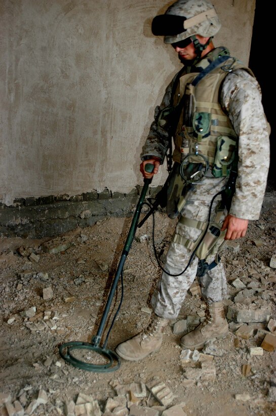 AR RAMADI, Iraq (April 2, 2005) -Twenty-year-old Cole E. Young, combat engineer, Company A, 1st Combat Engineer Battalion, of Green Bay, Wis., uses his metal detector to search for weapons and suspicious metals in a warehouse on the outskirts of the city here. Marines with 4th Platoon, Company B, 1st Battalion, 5th Marine Regiment and leathernecks of Company A, 1st Combat Engineer Battalion teamed up and discovered four 120 mm shells, a 155 mm shell; several live and empty 7.62 rounds, explosive detonation cord, a live fragmenting grenade and one rocket launcher during a five-hour search conducted on several acres of farmland along the banks of the Euphrates River on the edge of the city. Photo by Cpl. Tom Sloan
