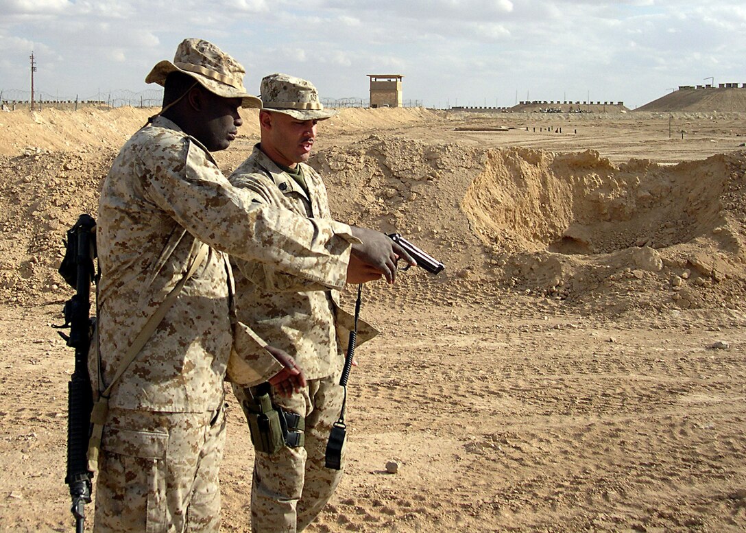 ASP Wolf, Al Anbar, Iraq--27-year-old Bronx, N.Y., native   SSgt. Steve Valencia a former drill instructor now a platoon serageant with 4th Combat Engineer Battalion,  gives Cpl. Dorian D. Brown advice on the properly shoot the M-9 hand gun. (Official USMC Photo by Corporal Ken Melton)