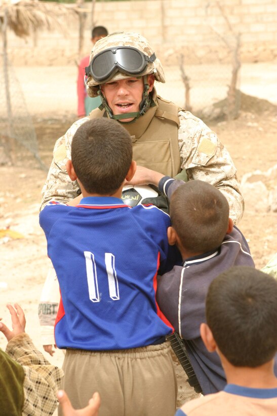 AR RAMADI, Iraq -- Staff Sgt. Jerome H. Murkerson, a 33-year-old Adger, Ala. native and staff non-commissioned officer-in-charge of the Camp Blue Diamond quick reaction force, hands a soccer ball to an Iraqi child, April 3.  The Marines handed out stuffed animals and soccer balls to Iraqi children to foster good relations with the citizens of the town.  Murkerson is a 1990 graduate of Oak Grove High School.  U.S. Marine Corps photo by Sgt. Stephen D'Alessio (RELEASED)