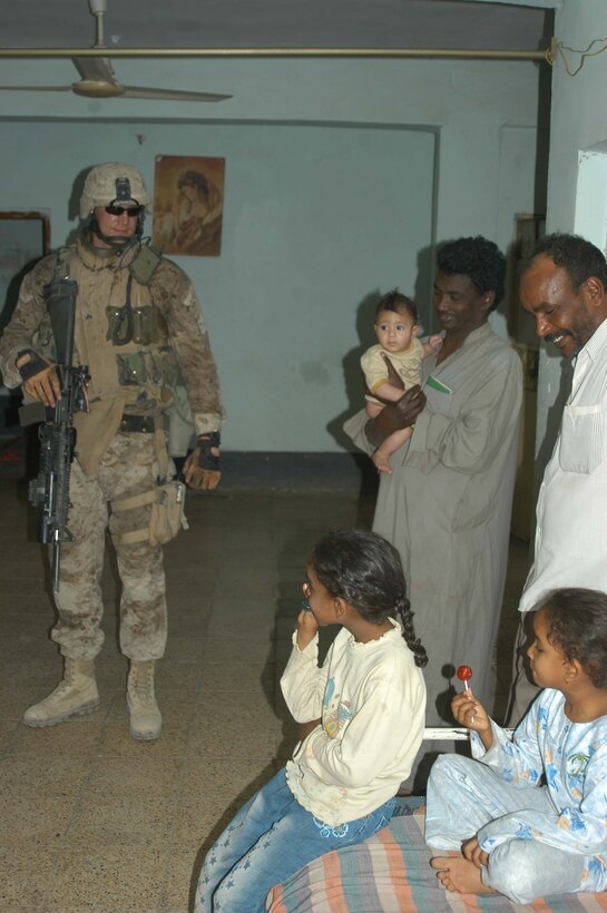 AR RAMADI, Iraq (April 24, 2005) - Corporal Christopher A. Hook, a rifleman and team leader with 2nd Squad, 3rd Platoon, Company A, 1st Battalion, 5th Marine Regiment, smiles at a young girl while his squad members search her house here. The 26-year-old from Chelsea, Va., and his fellow 3rd Platoon warriors cordoned off a two-block radius of Company A's area of operations and conducted a detailed search of its buildings and residents. The Marines didn't encounter any insurgents or threats during their three-hour-mission and returned safely to their firm base at Camp Hurricane Point without incident. Photo by Cpl. Tom Sloan