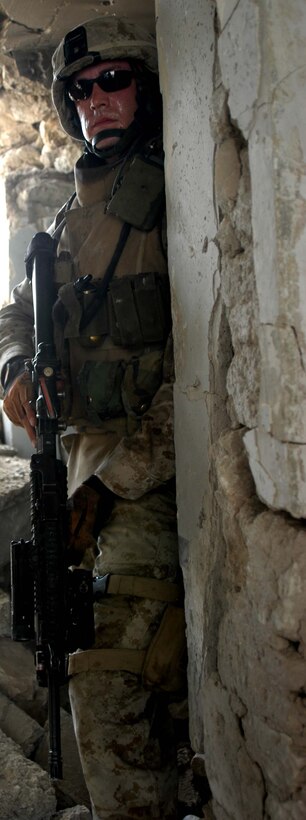 AR RAMADI, Iraq (April 24, 2005) - With sweat pouring down his face, Cpl. Christopher A. Hook, a rifleman and team leader with 2nd Squad, 3rd Platoon, Company A, 1st Battalion, 5th Marine Regiment, looks around the corner of an abandoned building he and his Marines just finished clearing here and sets his sites on another building across the street. The 26-year-old from Chelsea, Va., and his fellow 3rd Platoon warriors cordoned off a two-block radius of Company A's area of operations and conducted a detailed search of its buildings and residents. The Marines didn't encounter any insurgents or threats during their three-hour-mission and returned safely to their firm base at Camp Hurricane Point without incident. Photo by Cpl. Tom Sloan