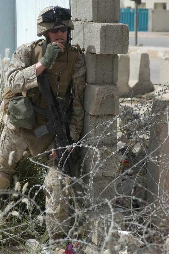 AR RAMADI, Iraq (April 24, 2005) - Corporal Troy C. Arnold, squad leader and rifleman with 2nd Squad, 3rd Platoon, Company A, 1st Battalion, 5th Marine Regiment, takes cover behind a wall in the city here and communicates with his squad members on his radio. The 27-year-old from Knoxville, Tenn., and his fellow 3rd Platoon warriors cordoned off a two-block radius of Company A's area of operations and conducted a detailed search of its buildings and residents. The Marines didn't encounter any insurgents or threats during their three-hour-mission and returned safely to their firm base at Camp Hurricane Point without incident. Photo by Cpl. Tom Sloan