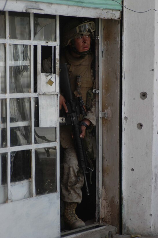 AR RAMADI, Iraq (April 24, 2005) - Lance Cpl. Mario R. De la Rosa, a rifleman with 2nd Squad, 3rd Platoon, Company A, 1st Battalion, 5th Marine Regiment, provides security from a building in the city here he and his Marines are searching. The 20-year-old from San Francisco and his fellow 3rd Platoon warriors cordoned off a two-block radius of Company A's area of operations and conducted a detailed search of its buildings and residents. The Marines didn't encounter any insurgents or threats during their three-hour-mission and returned safely to their firm base at Camp Hurricane Point without incident. Photo by Cpl. Tom Sloan