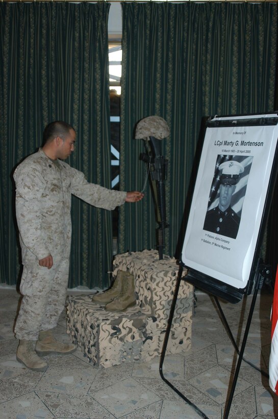 CAMP HURRICANE POINT, Ar Ramadi, Iraq (April 25, 2005) -Staff Sgt. Daniel Santiago, platoon sergeant for 1st Platoon, Company A, 1st Battalion, 5th Marine Regiment, holds the dog tags one of his Marines, Lance Cpl. Marty G. Mortenson, once wore and pays his final respects. Marines with 1st Battalion, 5th Marine Regiment, held a dual memorial ceremony in honor of Mortenson, 22, of Flagstaff, Ariz., and Cpl. Kelly M. Cannan, 21, of Lowville, N.Y. Both warriors were killed by the same improvised explosive device attack while traveling in a convoy April 20. They were on their third deployment supporting Operation Iraqi Freedom. Photo by Cpl. Tom Sloan
