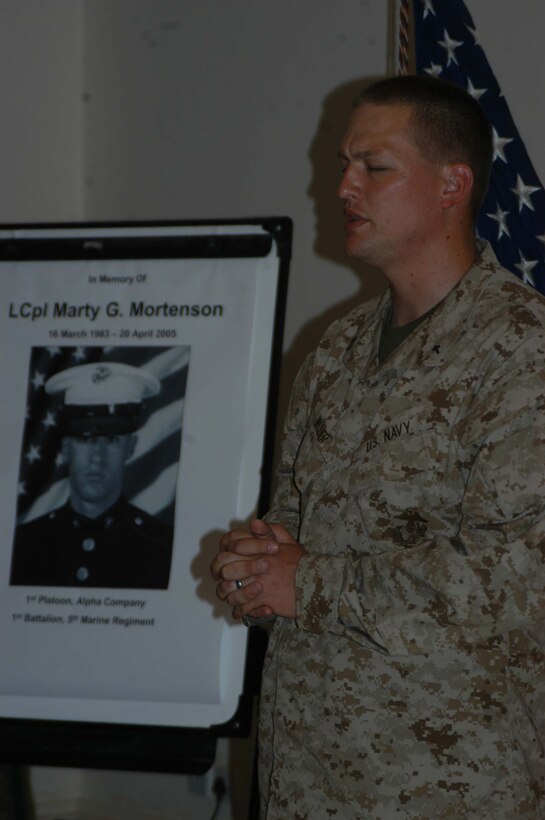 CAMP HURRICANE POINT, Ar Ramadi, Iraq (April 25, 2005) - Navy Lt. Aaron T. Miller, chaplain, 1st Battalion, 5th Marine Regiment, stands in front of photo of Lance Cpl. Marty G. Mortenson and prays as he delivers the invocation during a memorial ceremony here. Marines with 1st Battalion, 5th Marine Regiment, held a dual memorial ceremony in honor of Mortenson, 22, of Flagstaff, Ariz., and Cpl. Kelly M. Cannan, 21, of Lowville, N.Y. Both warriors were killed by the same improvised explosive device attack while traveling in a convoy April 20. They were on their third deployment supporting Operation Iraqi Freedom. Photo by Cpl. Tom Sloan