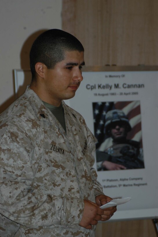 CAMP HURRICANE POINT, Ar Ramadi, Iraq (April 25, 2005) - Corporal Paul S. Zelaya, a rifleman and team leader with 1st Squad, 1st Platoon, Company A, 1st Battalion, 5th Marine Regiment, stands in front of a photo of his comrade, Cpl. Kelly M. Cannan, and tells what type of person his friend was to the Marines attending the memorial ceremony here. Marines with 1st Battalion, 5th Marine Regiment, held a dual memorial ceremony in honor of Cannan, 21, of Lowville, N.Y., and Lance Cpl. Marty G. Mortenson, 22, of Flagstaff, Ariz. Both warriors were killed by the same improvised explosive device attack while traveling in a convoy. They were on their third deployment supporting Operation Iraqi Freedom. Photo by Cpl. Tom Sloan