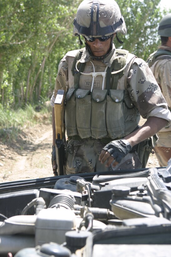 SAQLAWIYAH, Iraq - An Iraqi soldier looks underneath a vehicle's hood here April 27, looking for weapons and illegal contraband.  The local forces work alongside Marine personnel here to provide security and stability to the people of this formerly war-torn nation.