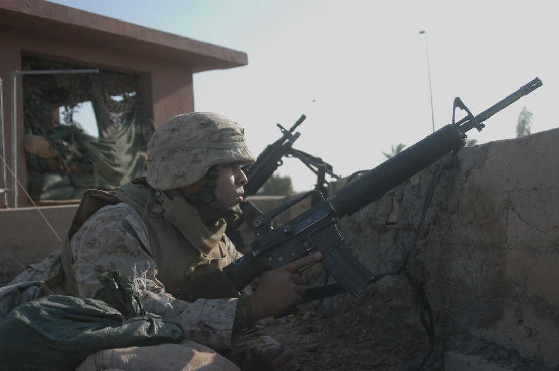 CAMP SNAKE PIT Ar Ramadi, Iraq (May 3, 2005) -- Lance Cpl. Salvador Ramirez, radio operator with Company C, 1st Battalion, 5th Marine Regiment, peaks over the edge of his company's command operations center building here and looks for insurgents. Insurgents attacked the 21-year-old from Chicago and other Company C Marines a few minutes past 8 a.m. The warriors successfully defended their camp from the attack and fought of the terrorists. Photo by Cpl. Tom Sloan
