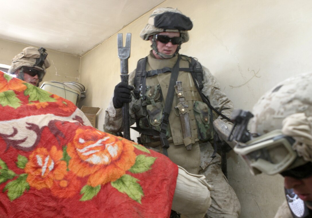 FALLUJAH, Iraq - Lance Cpl. Mike Hootman, machine gunner with 3rd Squad, 4th Platoon, Company B, 1st Battalion, 6th Marine Regiment, center, rushes down a flight of stairs with fellow Marines as they search for insurgents inside a residence here May 3.  Company B personnel worked alongside Iraqi Security Forces to apprehend an insurgent supporter known for laying improvised explosive devices here and recruiting others to do the same.