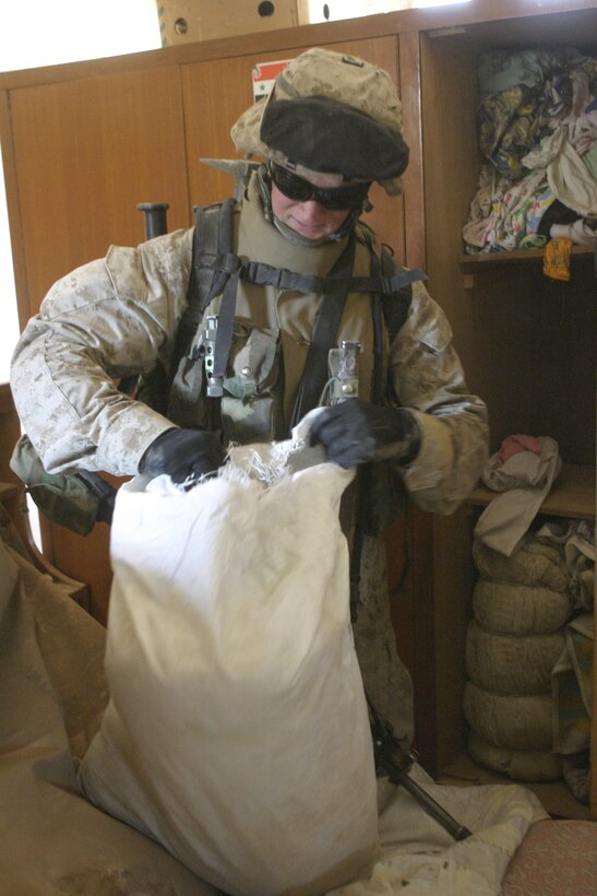 FALLUJAH, Iraq - Lance Cpl. Mike Hootman, machine gunner with 3rd Squad, 4th Platoon, Company B, 1st Battalion, 6th Marine Regiment, looks through a sack's contents for weapons and enemy intelligence inside a residence here May 3.  Company B personnel worked alongside Iraqi Security Forces to apprehend an insurgent supporter known for laying improvised explosive devices here and recruiting others to do the same.