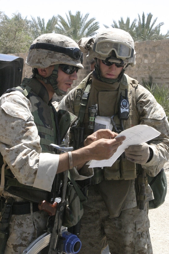 FALLUJAH, Iraq - 2nd Lt. Colin Chisholm, 3rd Platoon, Company B, 1st Battalion, 6th Marine Regiment's platoon commander, right, examines documents alongside Coco, one of Company B's translators, outside a residence here May 3.  Company B personnel worked alongside Iraqi Security Forces to apprehend an insurgent supporter known for laying improvised explosive devices here and recruiting others to do the same.