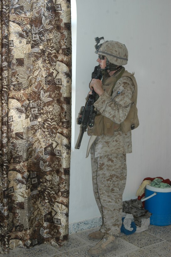 AR RAMADI Iraq (June 3, 2005) - Corporal Joseph P. Wilbourn, a mortar man and team leader with 1st Squad, 2nd Platoon, Company C, 1st Battalion, 5th Marine Regiment, looks out a window he and his Marines are using as a surveillance position during a mission in the city here. The 21-year-old from Santa Clarita, Calif., his fellow 1st Squad warriors and seven members of the Iraqi Security Forces conducted a mission to listen to messages a mosque was broadcasting over its loudspeakers during midday prayer. Photo by: Cpl. Tom Sloan