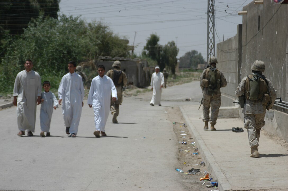 AR RAMADI Iraq (June 3, 2005) - Marines with 1st Squad, 2nd Platoon, Company C, 1st Battalion, 5th Marine Regiment, patrol past a group of Iraqi civilians during a mission here. The Marines and seven members of the Iraqi Security Forces conducted a mission to listen to messages a mosque was broadcasting over its loudspeakers during midday prayer. Marines with Company C are having a positive influence on the locals in their area of operations by working with the ISF. Photo by: Cpl. Tom Sloan