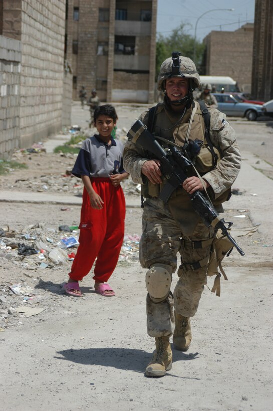 AR RAMADI Iraq (June 3, 2005) - Sergeant Seth D. Hickman, the squad leader of 1st Squad, 2nd Platoon, Company C, 1st Battalion, 5th Marine Regiment, smiles as he walks past an Iraqi child during a mission in the city here. The 24-year-old from Mason City, Iowa, his fellow 1st Squad warriors and seven members of the Iraqi Security Forces conducted a mission to listen to messages a mosque was broadcasting over its loudspeakers during midday prayer. Marines with Company C are having a positive influence on the locals in their area of operations by working with the ISF. Photo by: Cpl. Tom Sloan
