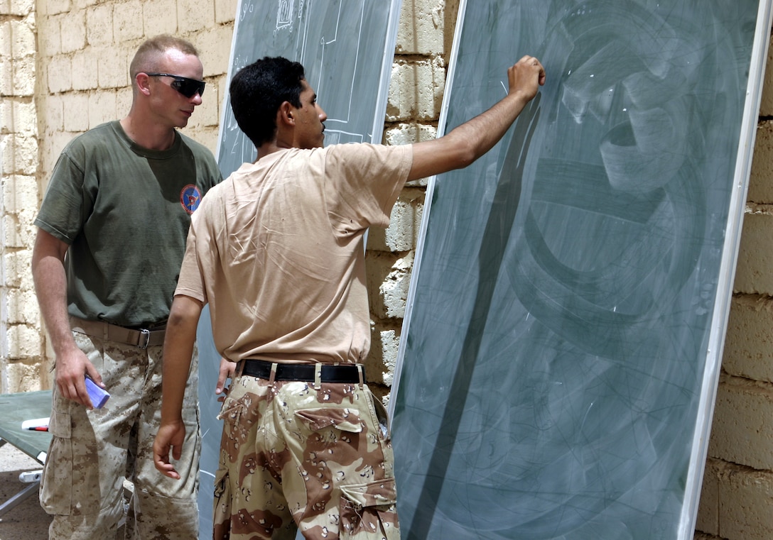 FALLUJAH, Iraq - Cpl. Shawn Campbell, an instructor with 1st Battalion, 6th Marine Regiment's Iraqi Security Forces training cadre, observes as an Iraqi soldier draws a tactical schematic during an infantry tactics class here Aug. 3.  Since mid-March, battalion personnel have trained approximately 600 Iraqi personnel on topics such as first aid in combat, infantry tactics, and convoy driving skills.  Iraqi forces are fully integrated into every operation the battalion's Marines and sailors conduct in and around the city.