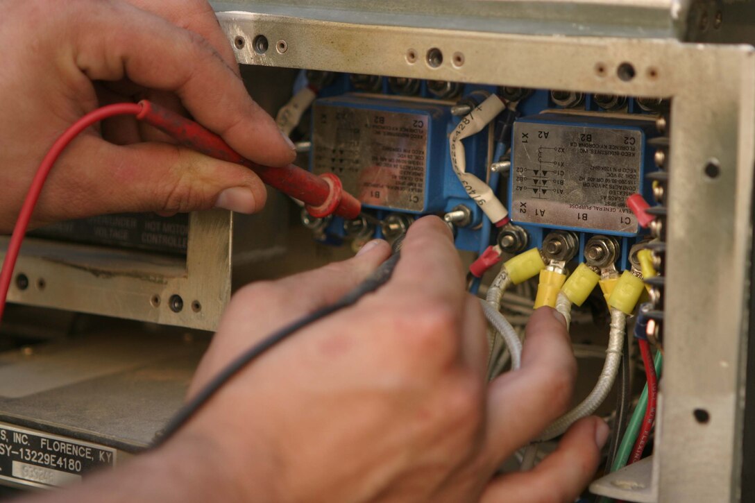 CAMP BLUE DIAMOND, RAMADI, Iraq -  Corporal Jeffery R. Lyskawa a refrigeration repair technician with Communications Company, Headquarter Battalion, 2nd Marine Division checks the voltage of one of the many military air conditioner's he maintains and repairs.  Lyskawa maintains and repairs dozens of air conditioners and generators that keep the Division's Communications Company up and running. Lyskawa has taken on the role of a pseudo "Maytag Man" for Communications Company which provides the main conduit for all internet, phone and radio communications flowing into and out of Camp Blue Diamond which houses the 2nd Marine Division's Headquarters. Official U.S. Marine Corps photo by Sgt. Ryan S. Scranton