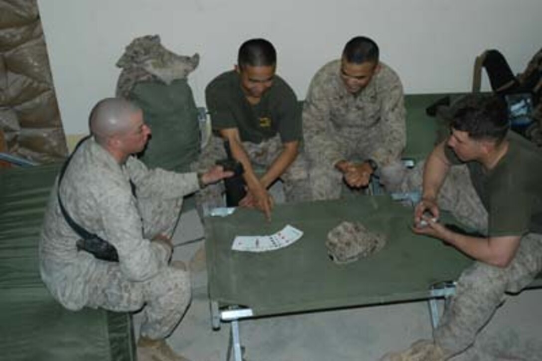 CAMP RAMADI, Iraq (March 3, 2005) --  Corporal Sam Heng, training non commissioned officer for training and operations, Headquarters and Service Company, 1st Battalion, 5th Marine Regiment, points at several cards spread out on a green military cot. The 22-year-old Cambodian from Seattle often entertains fellow Marines on their downtime with his card tricks, which makes him popular among many Marines in his unit. Lance Cpl. Jordan F. Sherwood(left), 22, of Roanoke, Va., a combat photographer for 1st Marine Division, Lance Cpl. John R. Cruz, 20, of Plainview, Texas, and Lance Cpl. Ryan G. Evans, 21, of Rome, Ga., both riflemen with H&S Company, 1/5, watch Heng perform. Heng taught himself two card tricks on his first deployment to Iraq during Operation Iraqi Freedom. He honed his skills during OIF 2 and puts them to good use entertaining other Marines on his third deployment in support of OIF. 1st Battalion, 5th Marines are in Ramadi on a seven-month deployment where they are conducting security and stabilization operations and training the Iraqi Security Forces.(Official United States Marine Corps photo by Cpl. Tom Sloan)