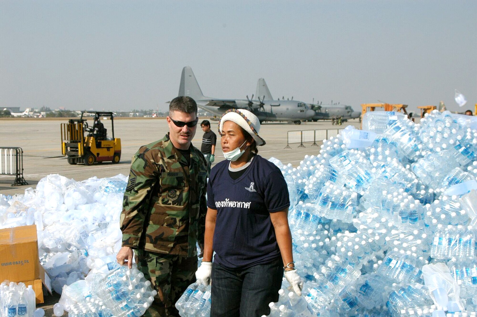 BANGKOK, Thailand -- An Airman here teams up with a Thai volunteer Jan. 1 to organize bottles of drinking water at the international airport.  He and 100 others from the 353rd Special Operations Group are flying supplies to the tsunami-hit areas of southern Thailand.  The 353rd SOG is assigned to Kadena Air Base, Japan.  (U.S. Air Force photo by Master Sgt. Michael Farris)