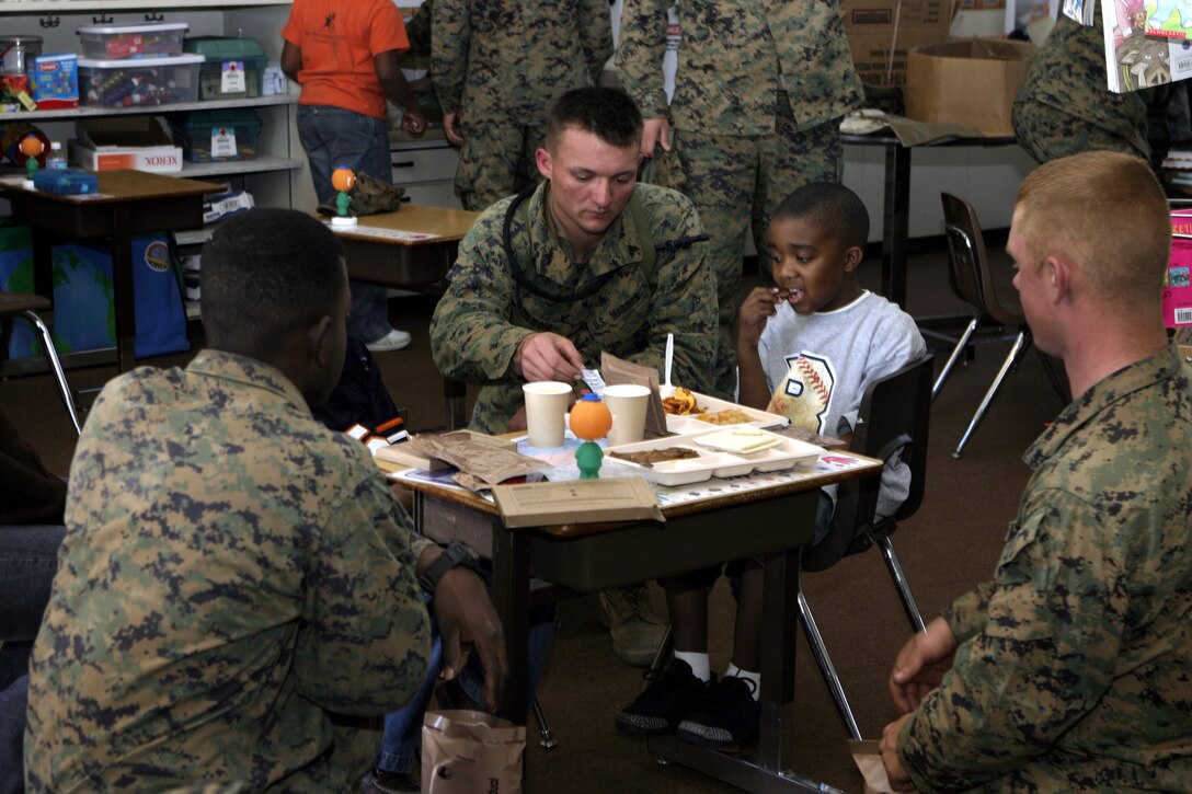 RIVERSIDE, Calif. - Cpl. Joshua A. Hazelwood, Company B, 1st Battalion, 6th Marine Regiment, and fellow Marines show an Arnold Heights alternative school student how to properly eat and prepare Meal Ready-to-Eat field rations.  1/6 personnel had spent a week conducting pre-deployment field training aboard March Air Reserve Base here, and ended their exercise by speaking to kids about the values of honor, courage, commitment and staying in school.  Photo by: Cpl. Mike Escobar