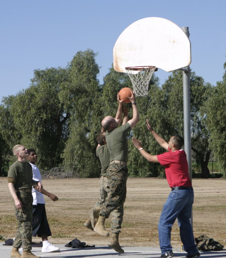 RIVERSIDE, Calif. - Navy Lt. Richard Ryan, 1st Battalion, 6th Marine Regiment chaplain, attempts a lay-up shot during a game of basketball Marines and sailors played against Arnold Heights alternative high school students here.  The troops had spent a week conducting pre-deployment field training aboard March Air Reserve Base here, and ended their exercise by speaking to kids about the values of honor, courage, commitment and staying in school.  Photo by: Cpl. Mike Escobar