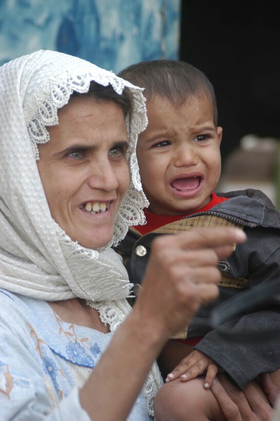 AR RAMADI, Iraq (May 4, 2005) -Standing outside her home here, the mother of an Iraqi boy with a server urinary tract infection smiles and expresses her appreciation for the help she received from Marines with 5th Civil Affairs Group, 1st Battalion, 5th Marine Regiment. If left untreated, the infection could've entered his kidneys and caused them to fail. Marines with 5th CAG coordinated for the boy to be taken to a local hospital to receive medical aid for his illness. Photo by Cpl. Tom Sloan