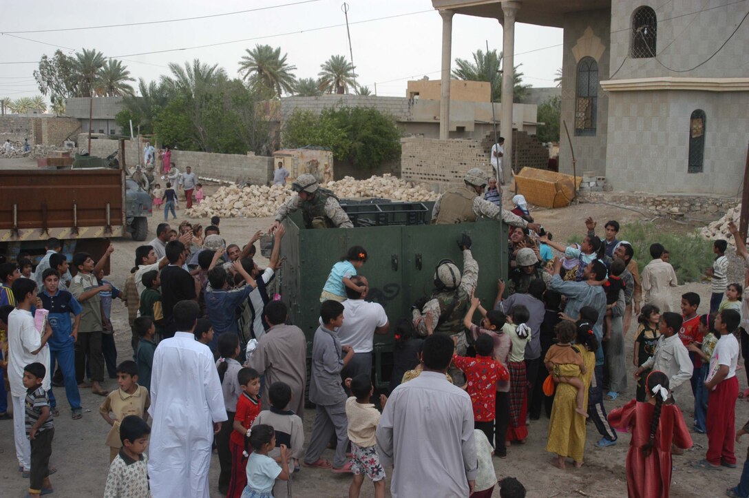 AR RAMADI, Iraq (May 4, 2005) -A city street here is bustling with happy Iraqi children as Marines with 5th Civil Affairs Group, 1st Battalion, 5th Marine Regiment, present them with gifts of soccer balls, clothes, dolls and wristwatches. The effort was a diversion tactic designed to keep the insurgency from learning the real reason for their visit. Marines with 5th CAG coordinated for an Iraqi boy with a server urinary tract infection to receive treatment at a local hospital. Photo by Cpl. Tom Sloan