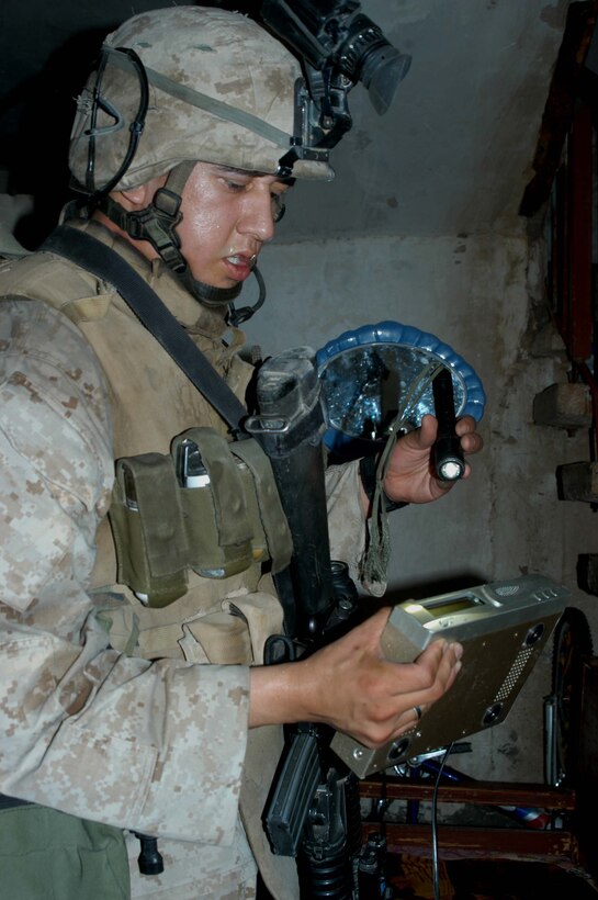AR RAMADI Iraq (July 4, 2005) - Corporal Sergio Hernandez, a rifleman and team leader with 3rd Squad, 3rd Platoon, Company A, 1st Battalion, 5th Marine Regiment, inspects an electronic device he found while searching a house in the city here during a mission July 4. The 22-year-old from Hanford, Calif., and his fellow Marines captured six insurgents during a raid between 2 a.m. and 4 a.m., which made for a unique and memorable Independence Day. Hernandez has grown accustomed to being away from his family and friends during such holidays. The 2001 Hanford High School West Campus graduate is currently on his third deployment in support of Operation Iraqi Freedom. Photo by: Cpl. Tom Sloan