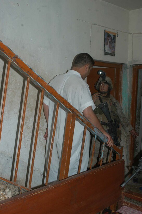 AR RAMADI Iraq (July 4, 2005) - Corporal Sergio Hernandez, a rifleman and team leader with 3rd Squad, 3rd Platoon, Company A, 1st Battalion, 5th Marine Regiment, motions for a man to come down a flight of stairs while he searches a house in the city here during a mission July 4. The 22-year-old from Hanford, Calif., and his fellow Marines captured six insurgents during a raid between 2 a.m. and 4 a.m., which made for a unique and memorable Independence Day. Hernandez has grown accustomed to being away from his family and friends during such holidays. The 2001 Hanford High School West Campus graduate is currently on his third deployment in support of Operation Iraqi Freedom. Photo by: Cpl. Tom Sloan