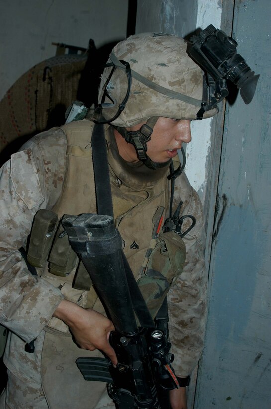AR RAMADI Iraq (July 4, 2005) - Corporal Sergio Hernandez, a rifleman and team leader with 3rd Squad, 3rd Platoon, Company A, 1st Battalion, 5th Marine Regiment, quickly enters a house in the city here during a mission July 4. The 22-year-old from Hanford, Calif., and his fellow Marines captured six insurgents during a raid between 2 a.m. and 4 a.m., which made for a unique and memorable Independence Day. Hernandez has grown accustomed to being away from his family and friends during such holidays. The 2001 Hanford High School West Campus graduate is currently on his third deployment in support of Operation Iraqi Freedom. Photo by: Cpl. Tom Sloan