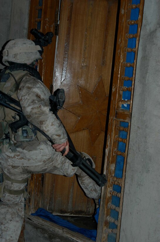 AR RAMADI Iraq (July 4, 2005) - Lance Cpl. Eric L. Roskam, an assault man with 3rd Squad, 3rd Platoon, Company A, 1st Battalion, 5th Marine Regiment, kicks in the door to a house during an early-morning mission in the city here July 4. The 20-year-old from Shelby, Mich., and his fellow Marines captured six insurgents during a raid between 2 a.m. and 4 a.m., which made for a unique and memorable Independence Day. Photo by: Cpl. Tom Sloan