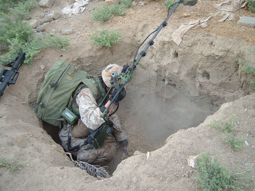 AL QA'IM, Iraq (June 4, 2005)- A Marine combat engineer with Company A, 4th Combat Engineer Battalion, Regimental Combat Team-2 searches a hole after finding a weapons cache during Operation River Round-up here. Official U.S. Marine Corps photo by Lance Cpl. Lucian Friel (RELEASED)