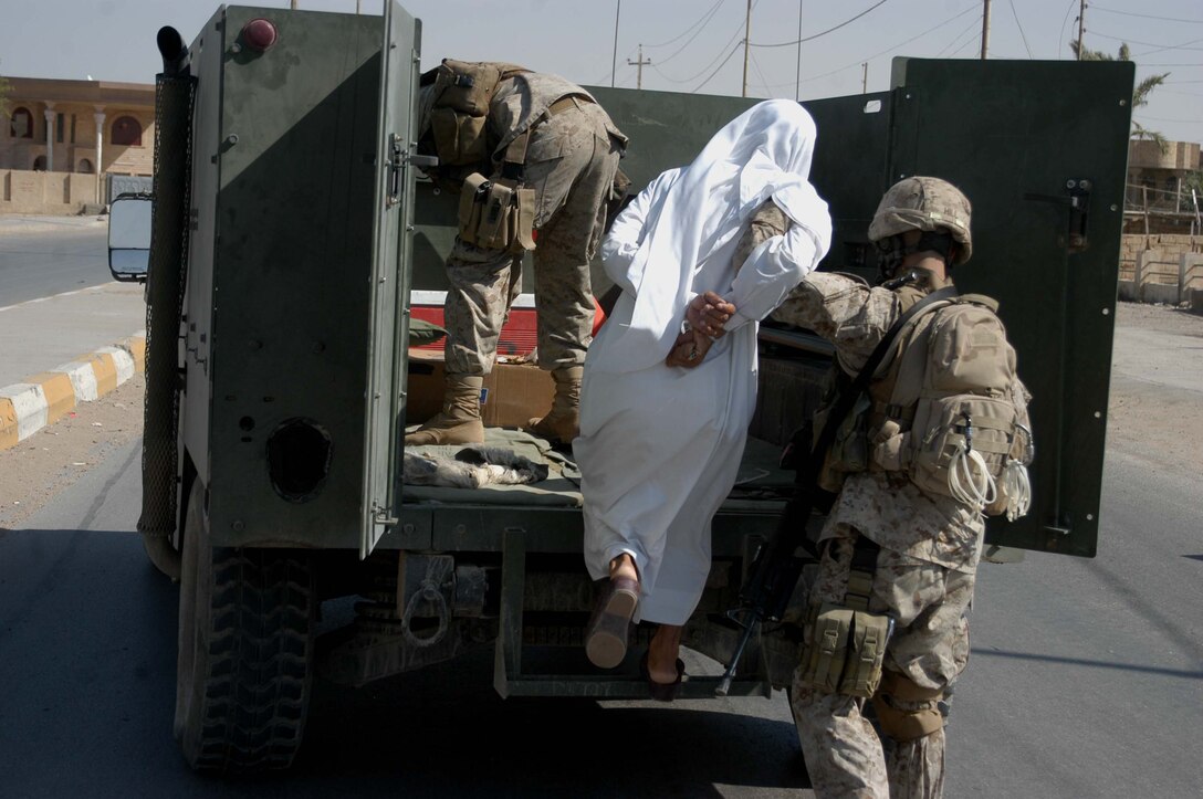 AR RAMADI Iraq (Aug. 4, 2005) -Sergeant Jade C. Hill, the squad leader of 3rd Squad, 2nd Platoon, Company A, 1st Battalion, 5th Marine Regiment, loads a suspected insurgent into the back of a humvee during a mission in the city here Aug. 4. Hill, a 21-year-old from Westminster, Md., and other Marines with 2nd Platoon captured the man while conducting random vehicle and personnel searches throughout the city in an effort to capture insurgents and seize weapons. The man they caught was believed by Marine officials to be responsible for attacking Marines with improvised explosives. Photo by: Cpl. Tom Sloan