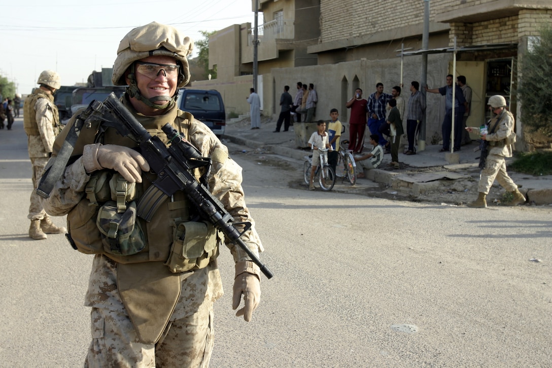 FALLUJAH, Iraq - Gunnery Sgt. Walter Diggs, 4th Combined Anti-Armor Team's commander, Weapons Company, 1st Battalion, 6th Marine Regiment, patrols the streets here as his Marines provide area security and converse with some locals.  Fourth CAAT Marines routinely patrol Fallujah's streets aboard their armored trucks and on foot to deter insurgent activity and interact with the community.